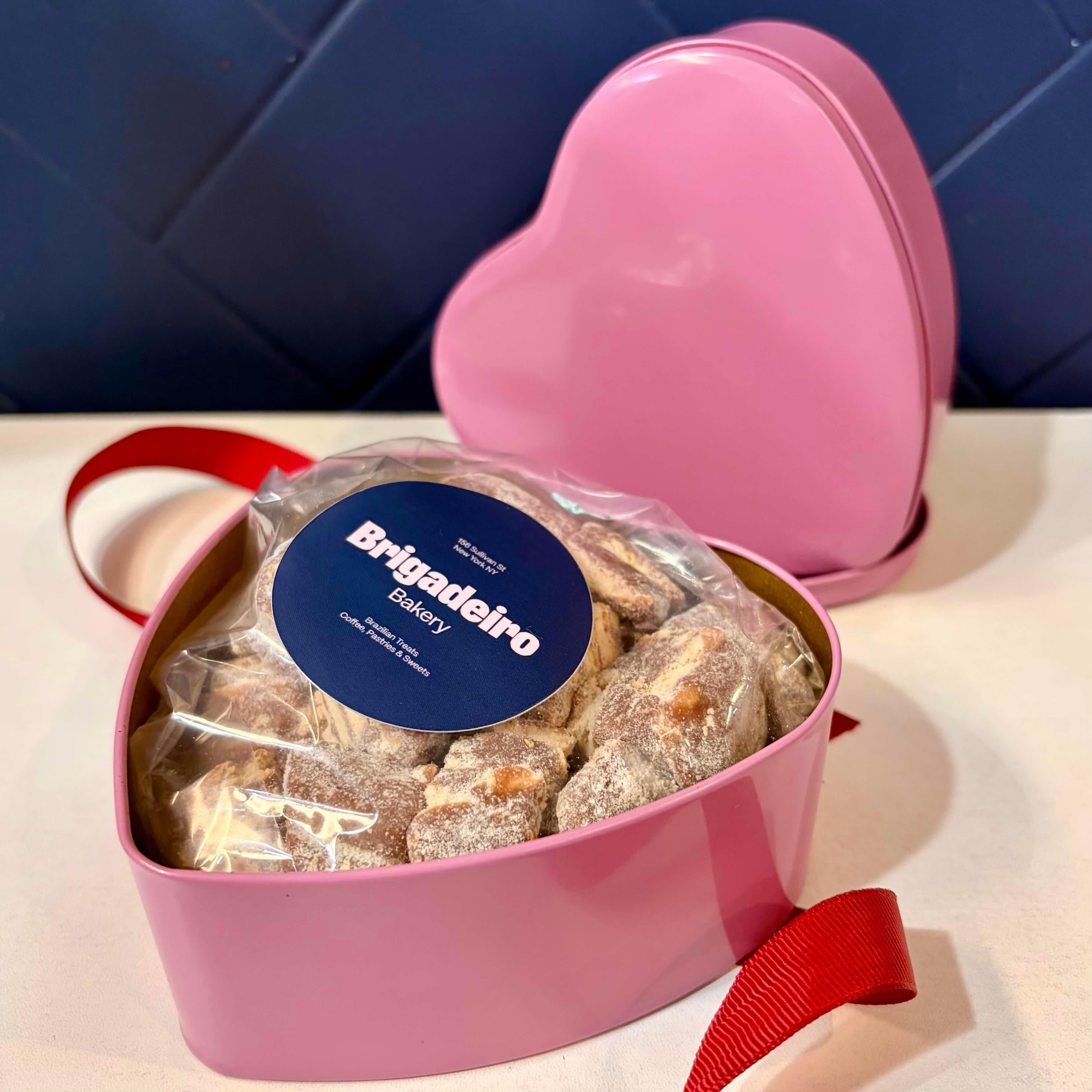 Brigadeiro Bakery: Mini Palhas Heart Tin — Valentine’s Day Special , 2 x $24.00
Back by popular demand — with a Valentine’s twist 💕
Our Mini Palhas Heart Tin was inspired by how much you loved this treat during the holidays, so we dressed it up for Valentine’s Day in a festive heart-shaped tin, perfect for gifting or treating yourself.
Inside, you’ll find our delicious Palhas cut into bite-size mini cubes, making them easy to share (or snack on all by yourself — we won’t judge). Rich, indulgent, and full of flavor, these mini treats are made to be enjoyed one piece at a time.

What Are Palhas?
Palhas are a classic Brazilian sweet made with creamy chocolate brigadeiro mixed with crushed butter cookies for the perfect balance of smooth and crunchy. The mixture is then shaped, chilled, and cut into bite-size pieces.

Whether you’re celebrating with someone special, bringing a sweet gift to a gathering, or keeping it close for cozy moments, this Valentine’s tin is a fun and delicious way to spread the love.

Why You’ll Love It:
Heart-shaped Valentine’s Day tin
Filled with mini Palhas cubes, perfect for sharing
Inspired by our best-selling holiday favorite
Great for gifting, entertaining, or personal indulgence