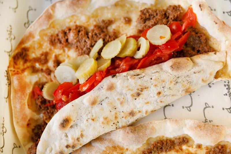 Manousheh: Sujuk bi ajine, 2 x $8.00
middle eastern beef sausage prepared with
red wine, garlic, tomato, and onion baked on our crispy flatbread